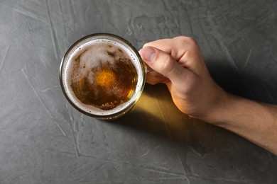 Photo of Man with glass mug of beer at grey table, top view
