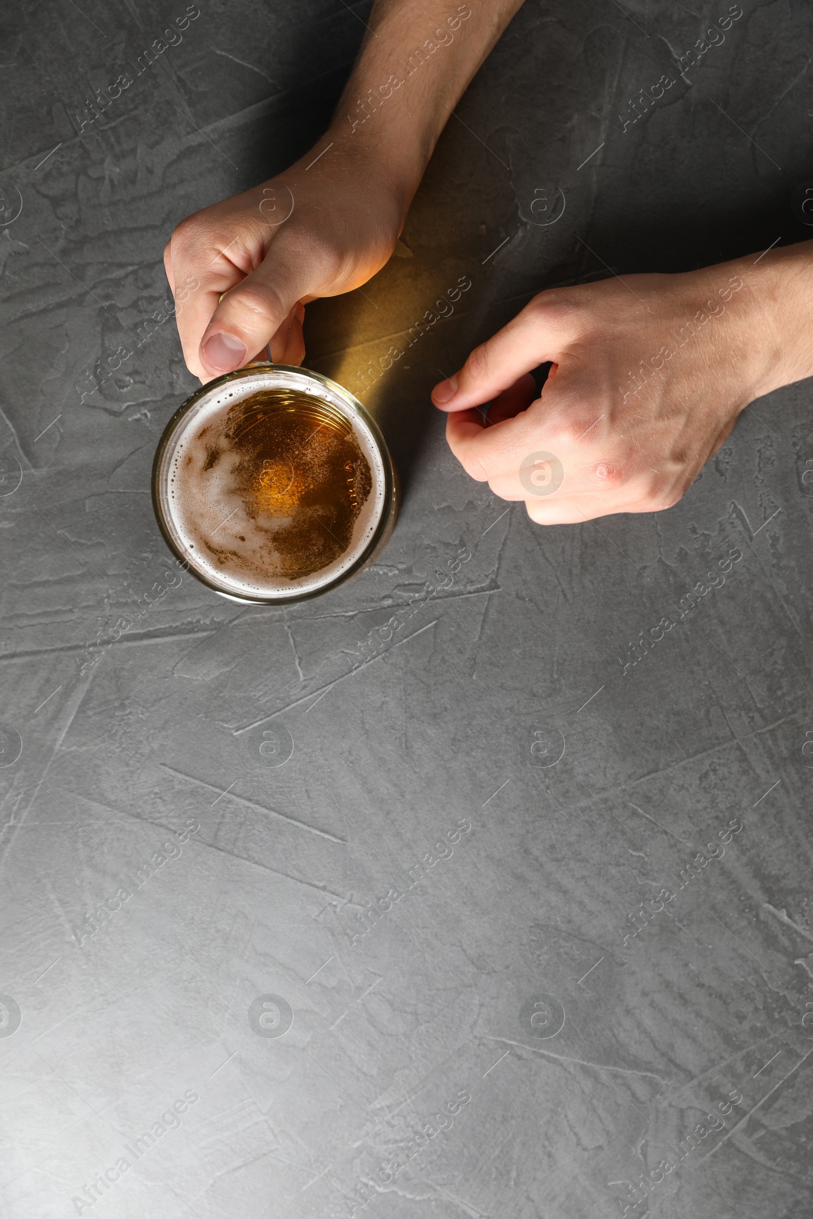 Man with glass mug of beer at grey table, top view. Space for text Photo of Man with glass mug of beer at grey table, top view. Space for text