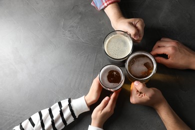 Photo of Friends with glasses of beer at grey table, top view. Space for text