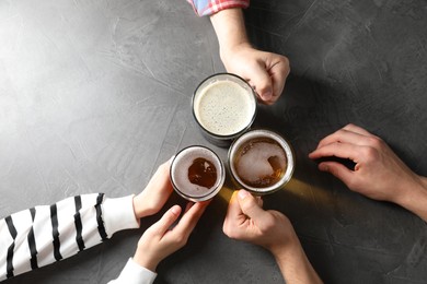 Photo of Friends with glasses of beer at grey table, top view
