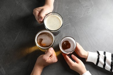 Photo of Friends with glasses of beer at grey table, top view
