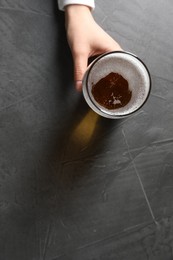 Photo of Woman with glass of beer at grey table, top view. Space for text