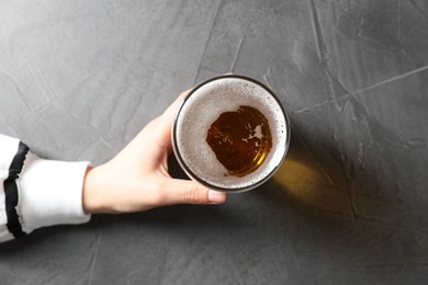 Photo of Woman with glass of beer at grey table, top view