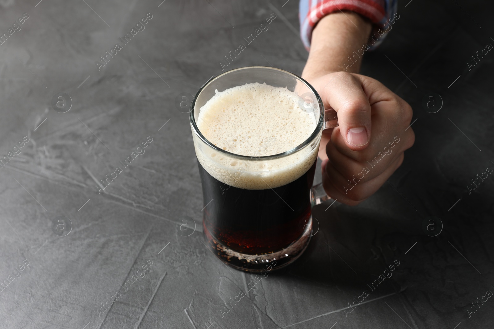 Man with glass mug of beer at grey table, closeup. Space for text Photo of Man with glass mug of beer at grey table, closeup. Space for text