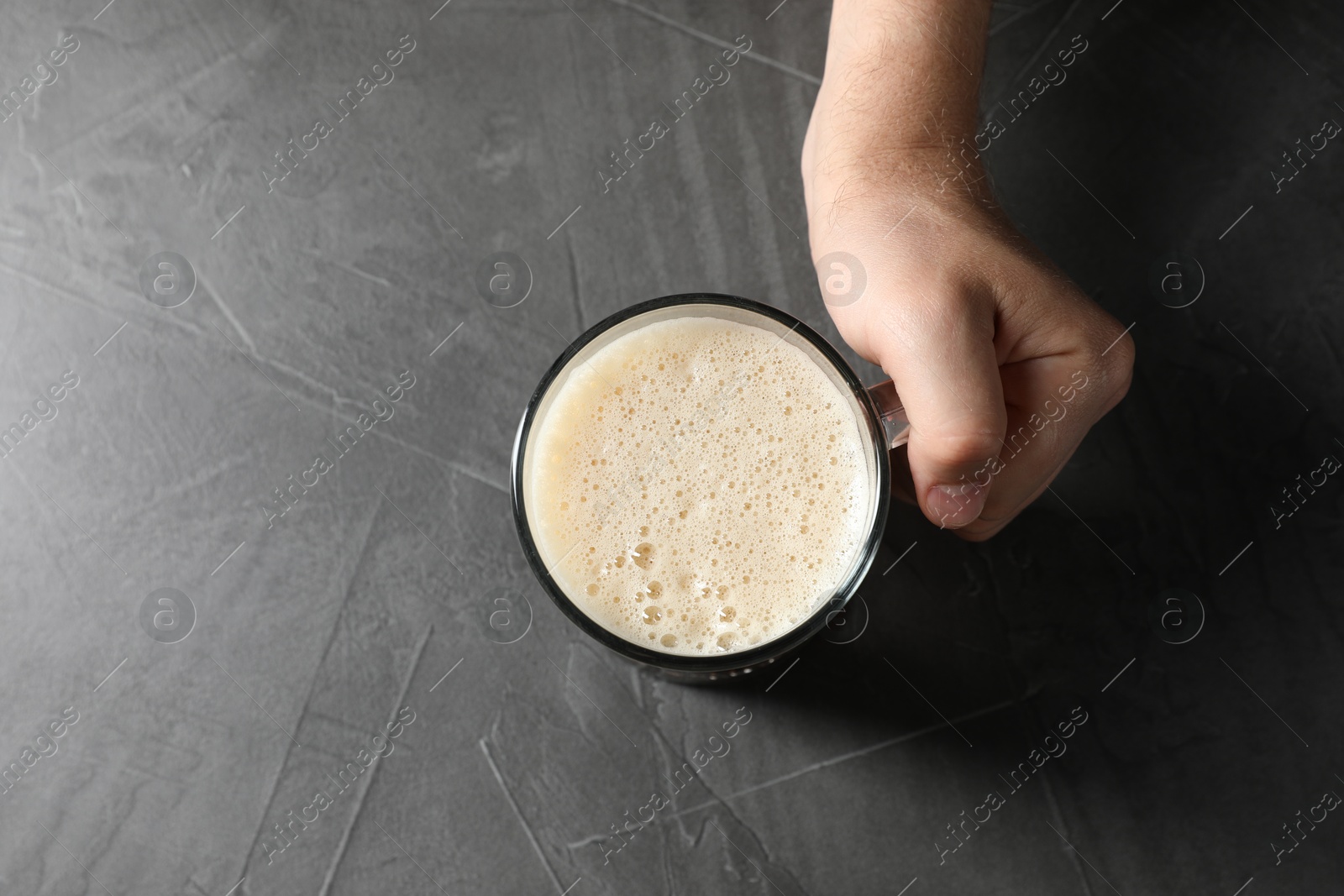 Photo of Man with glass mug of beer at grey table, top view. Space for text