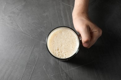 Photo of Man with glass mug of beer at grey table, top view. Space for text
