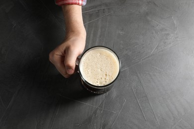 Photo of Man with glass mug of beer at grey table, top view
