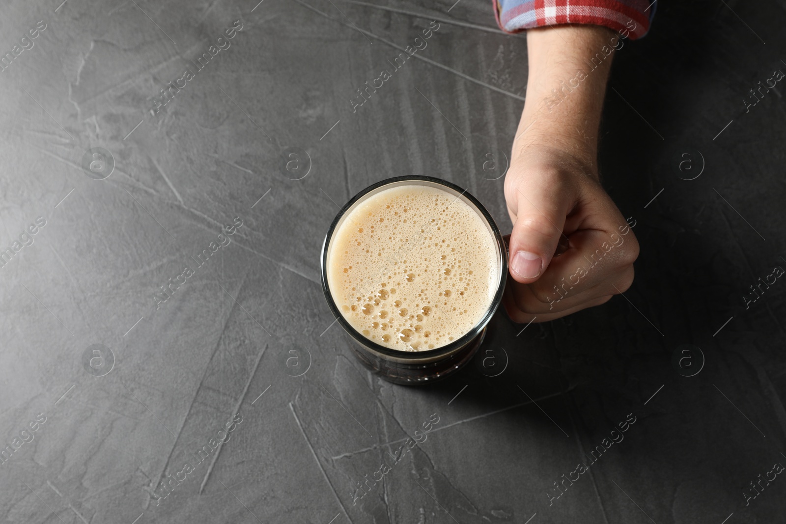 Photo of Man with glass mug of beer at grey table, top view. Space for text