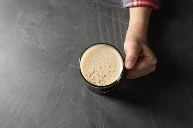 Photo of Man with glass mug of beer at grey table, top view. Space for text