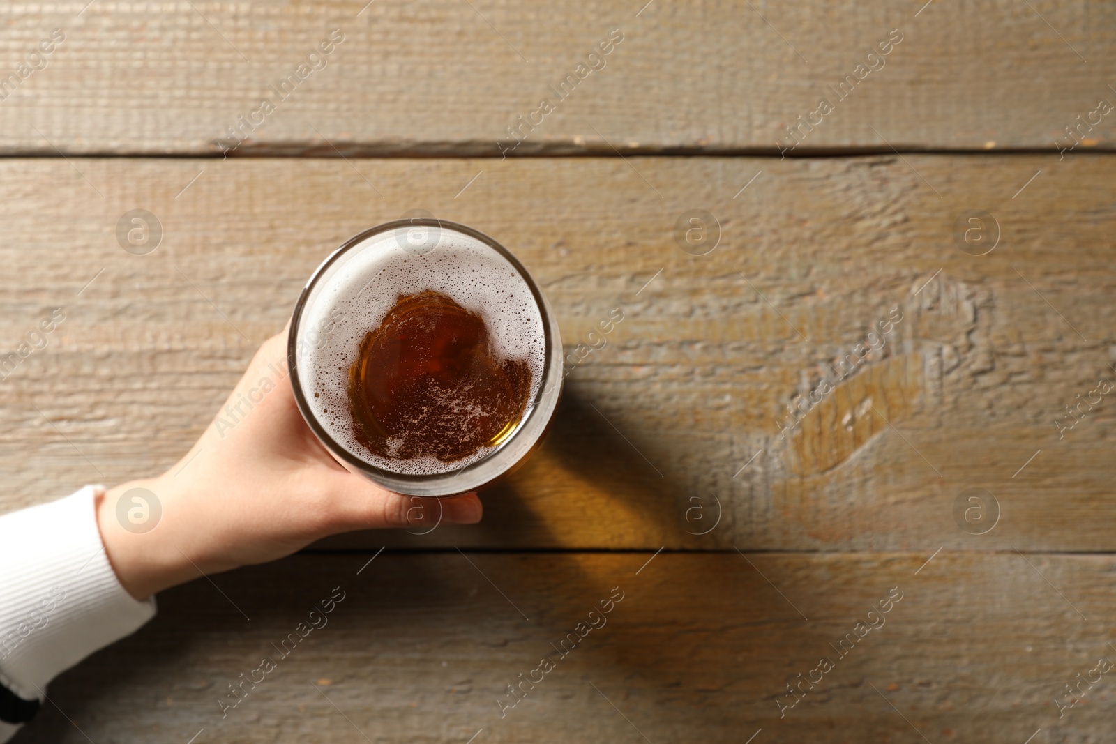 Photo of Woman with glass of beer at wooden table, top view. Space for text