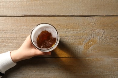 Photo of Woman with glass of beer at wooden table, top view. Space for text