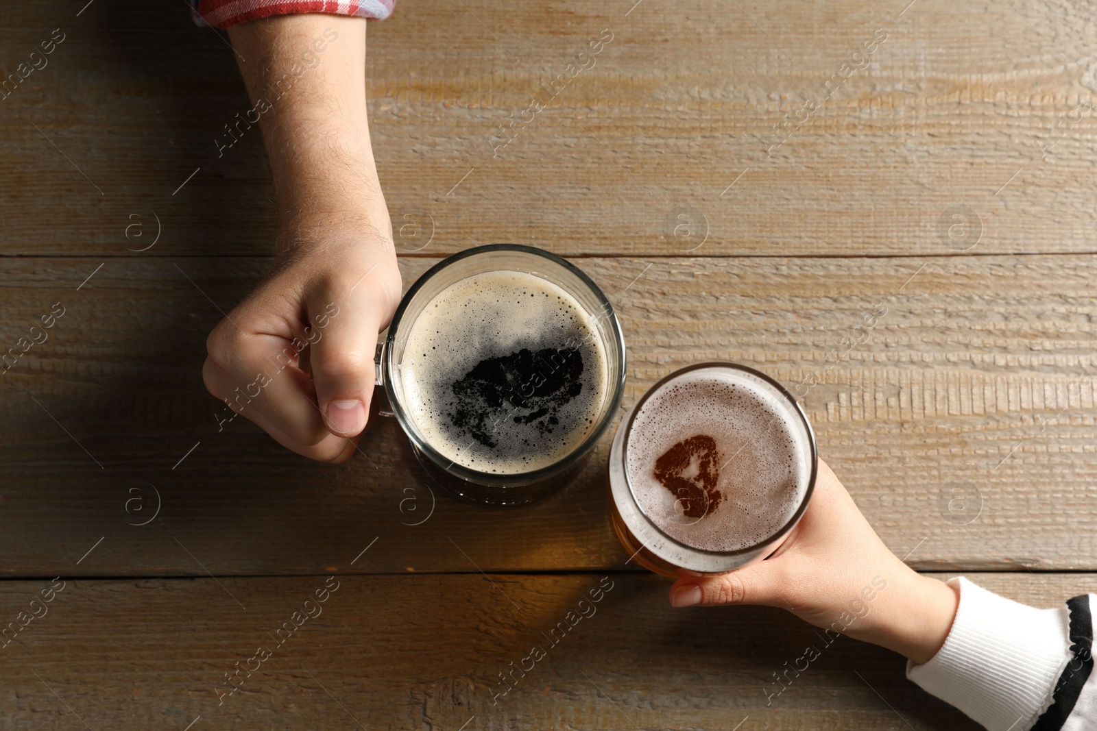 Friends with glasses of beer at wooden table, top view Photo of Friends with glasses of beer at wooden table, top view