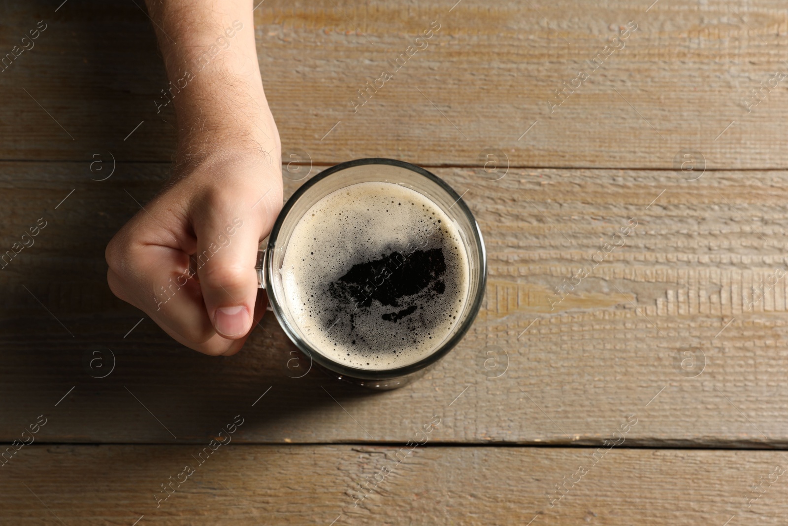 Photo of Man with glass mug of beer at wooden table, top view