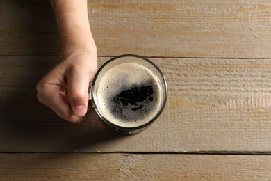 Photo of Man with glass mug of beer at wooden table, top view