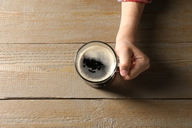 Photo of Man with glass mug of beer at wooden table, top view. Space for text
