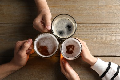 Photo of Friends with glasses of beer at wooden table, top view