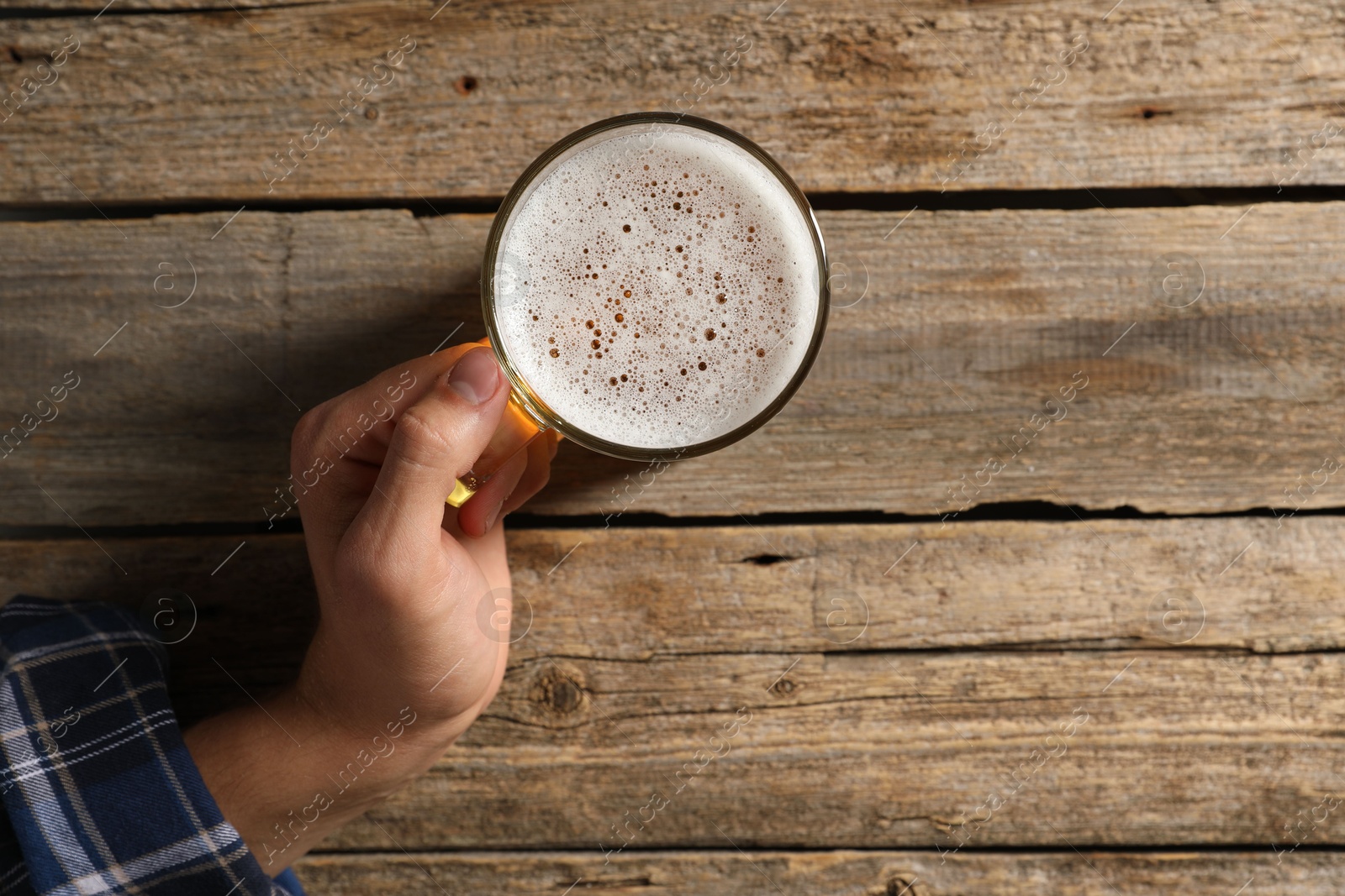Photo of Man with glass mug of beer at wooden table, top view. Space for text