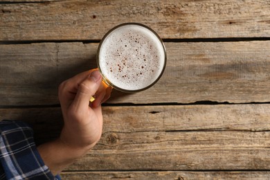 Photo of Man with glass mug of beer at wooden table, top view. Space for text