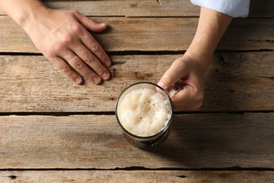 Photo of Man with glass mug of beer at wooden table, top view