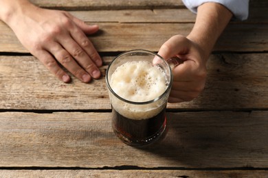 Photo of Man with glass mug of beer at wooden table, above view