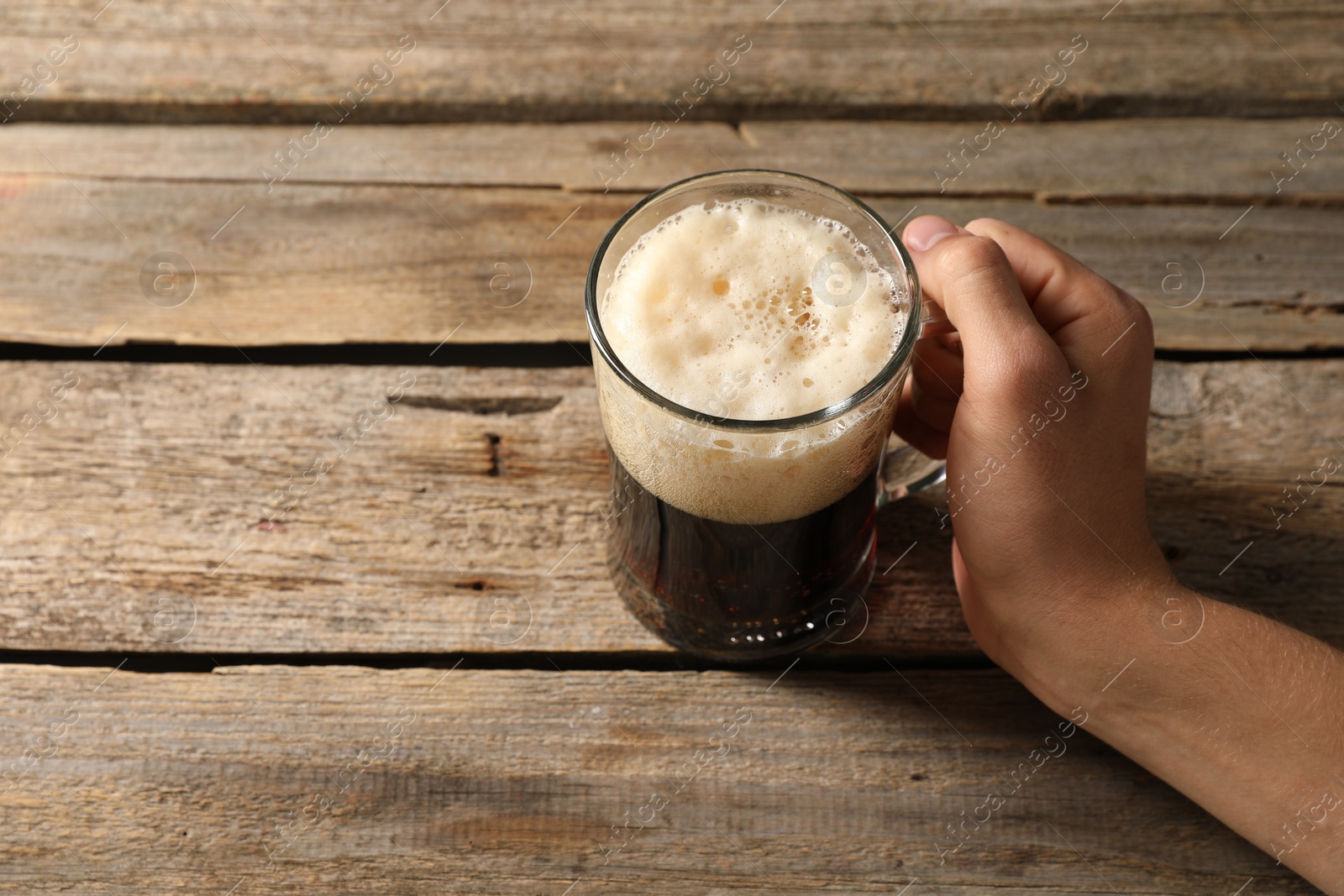 Photo of Man with glass mug of beer at wooden table, above view. Space for text