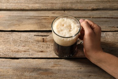 Photo of Man with glass mug of beer at wooden table, above view. Space for text