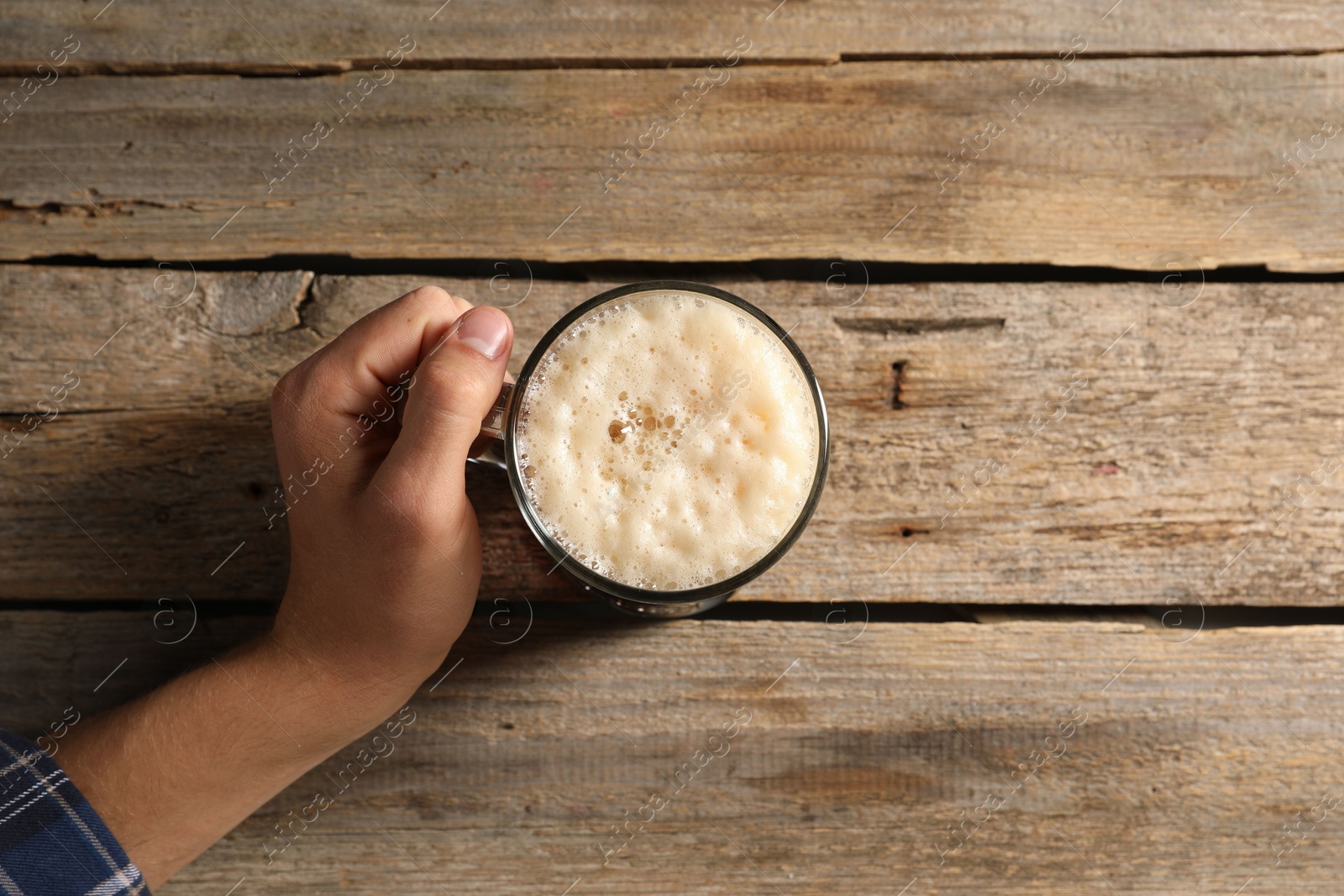 Photo of Man with glass mug of beer at wooden table, top view. Space for text