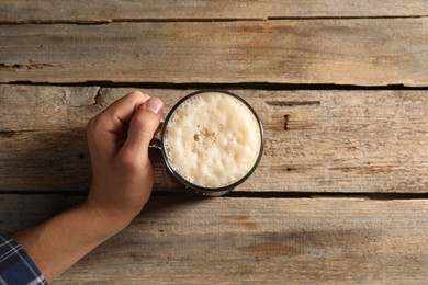 Photo of Man with glass mug of beer at wooden table, top view. Space for text