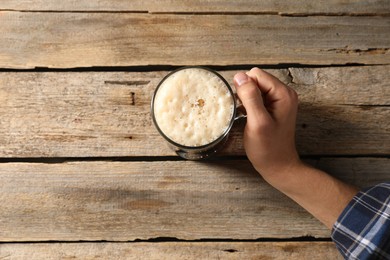 Photo of Man with glass mug of beer at wooden table, top view. Space for text
