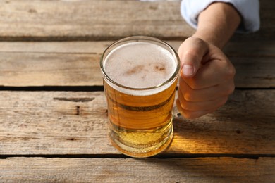 Photo of Man with glass mug of beer at wooden table, closeup