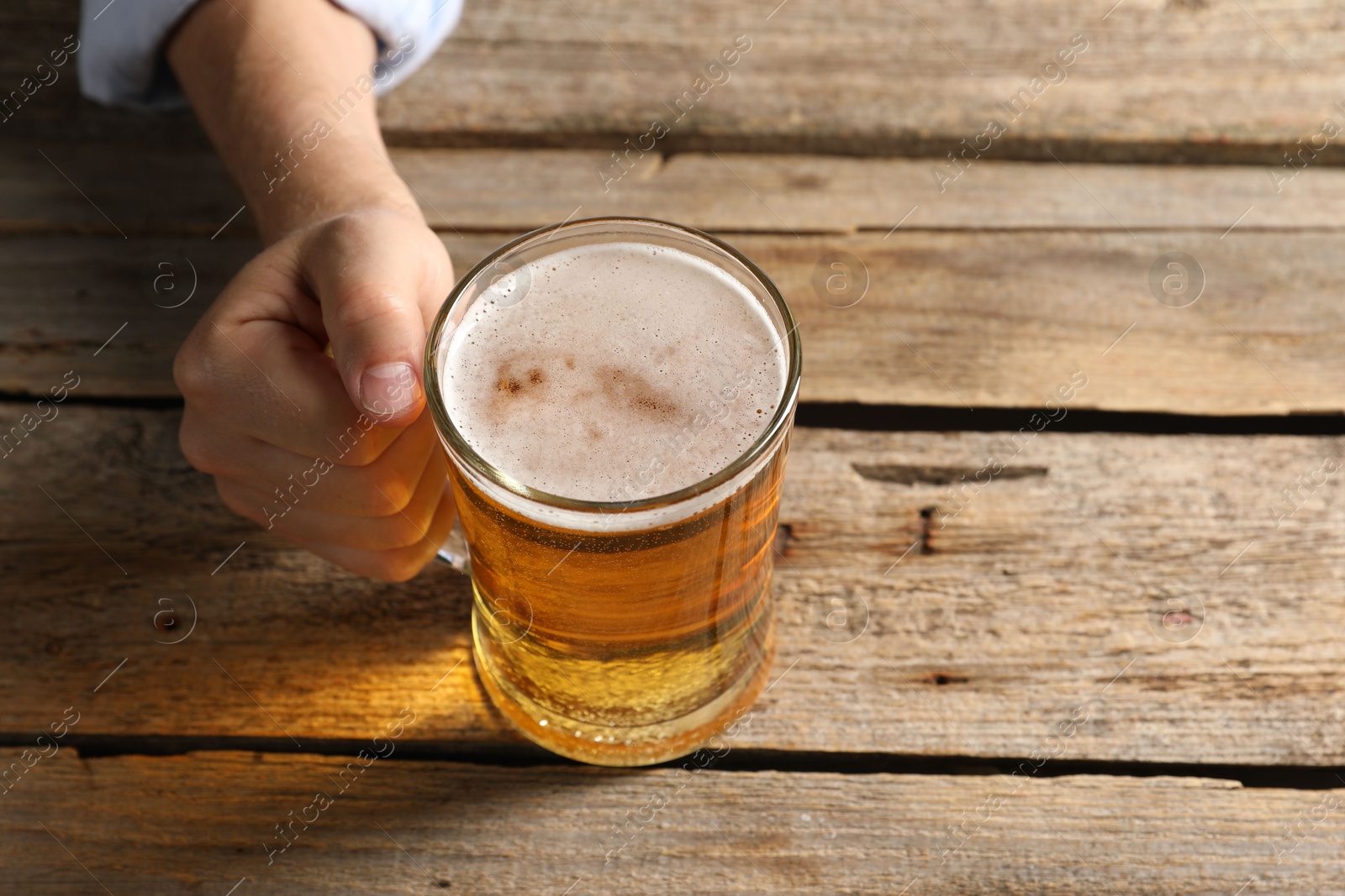 Photo of Man with glass mug of beer at wooden table, above view. Space for text