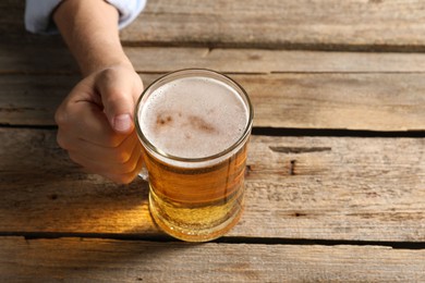 Photo of Man with glass mug of beer at wooden table, above view. Space for text