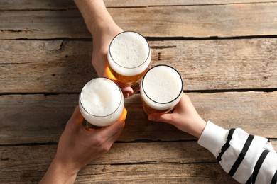 Photo of Friends with glasses of beer at wooden table, top view