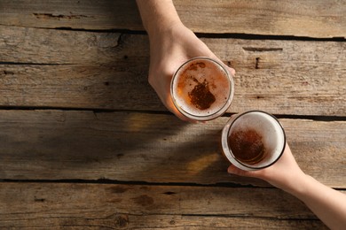 Photo of Friends with glasses of beer at wooden table, top view. Space for text