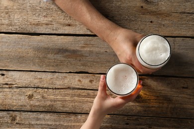 Photo of Friends with glasses of beer at wooden table, top view. Space for text