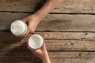 Photo of Friends with glasses of beer at wooden table, top view. Space for text