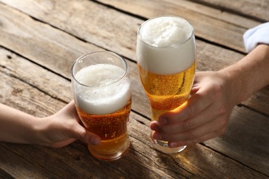Photo of Friends with glasses of beer at wooden table, closeup