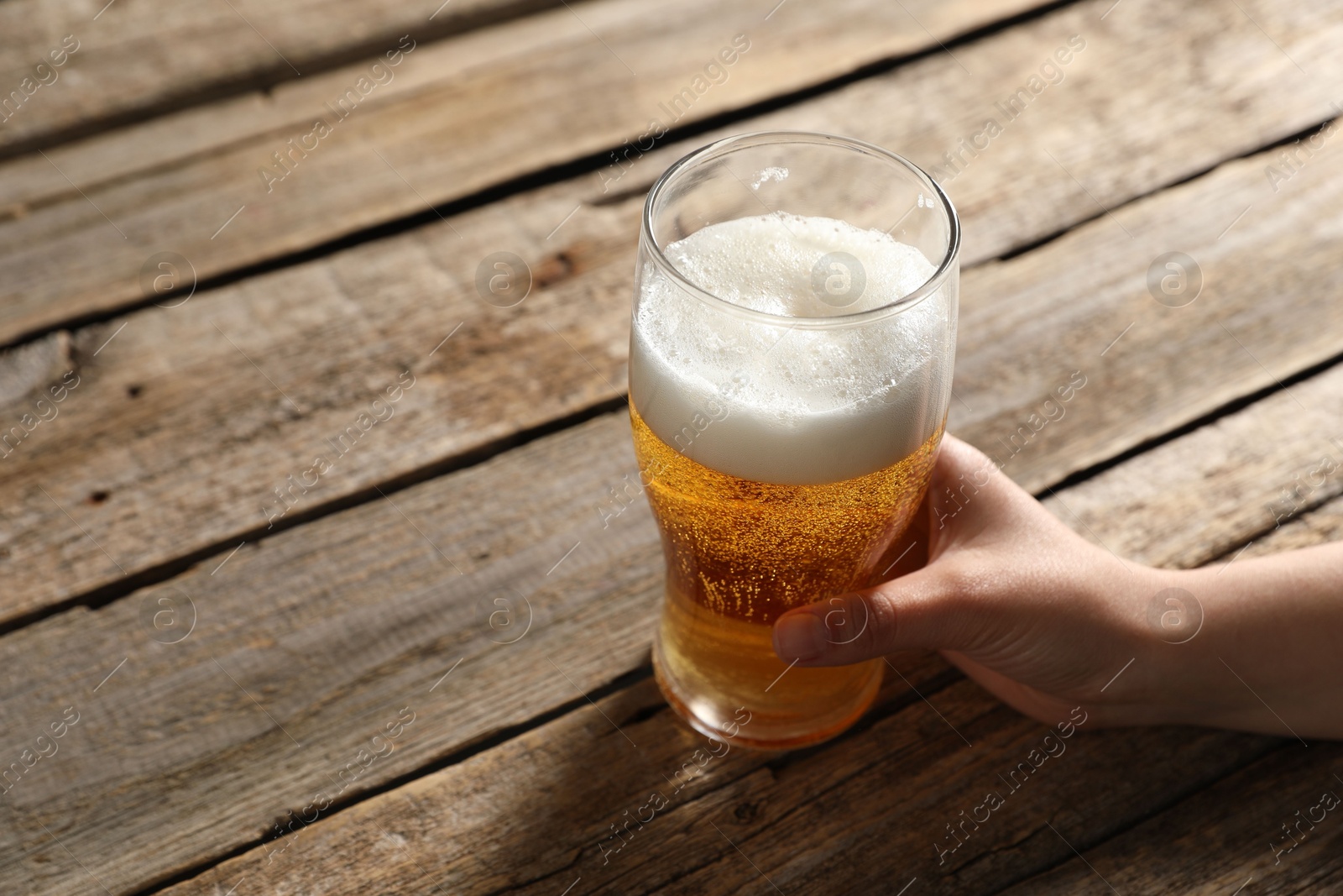 Woman with glass of beer at wooden table, closeup. Space for text Photo of Woman with glass of beer at wooden table, closeup. Space for text
