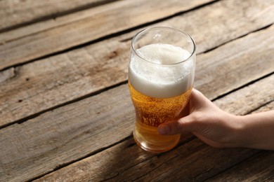 Photo of Woman with glass of beer at wooden table, closeup. Space for text