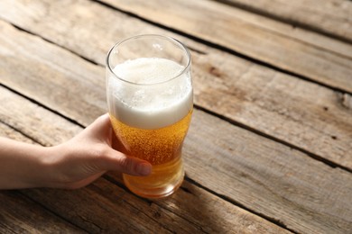 Photo of Woman with glass of beer at wooden table, closeup. Space for text