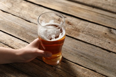 Photo of Woman with glass of beer at wooden table, closeup. Space for text