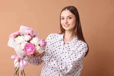 Photo of Woman with beautiful bouquet of peonies on dark beige background