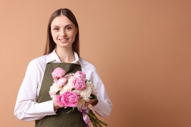 Photo of Florist with beautiful bouquet of peonies on dark beige background, space for text