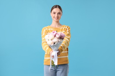 Photo of Woman with beautiful bouquet of peonies on light blue background