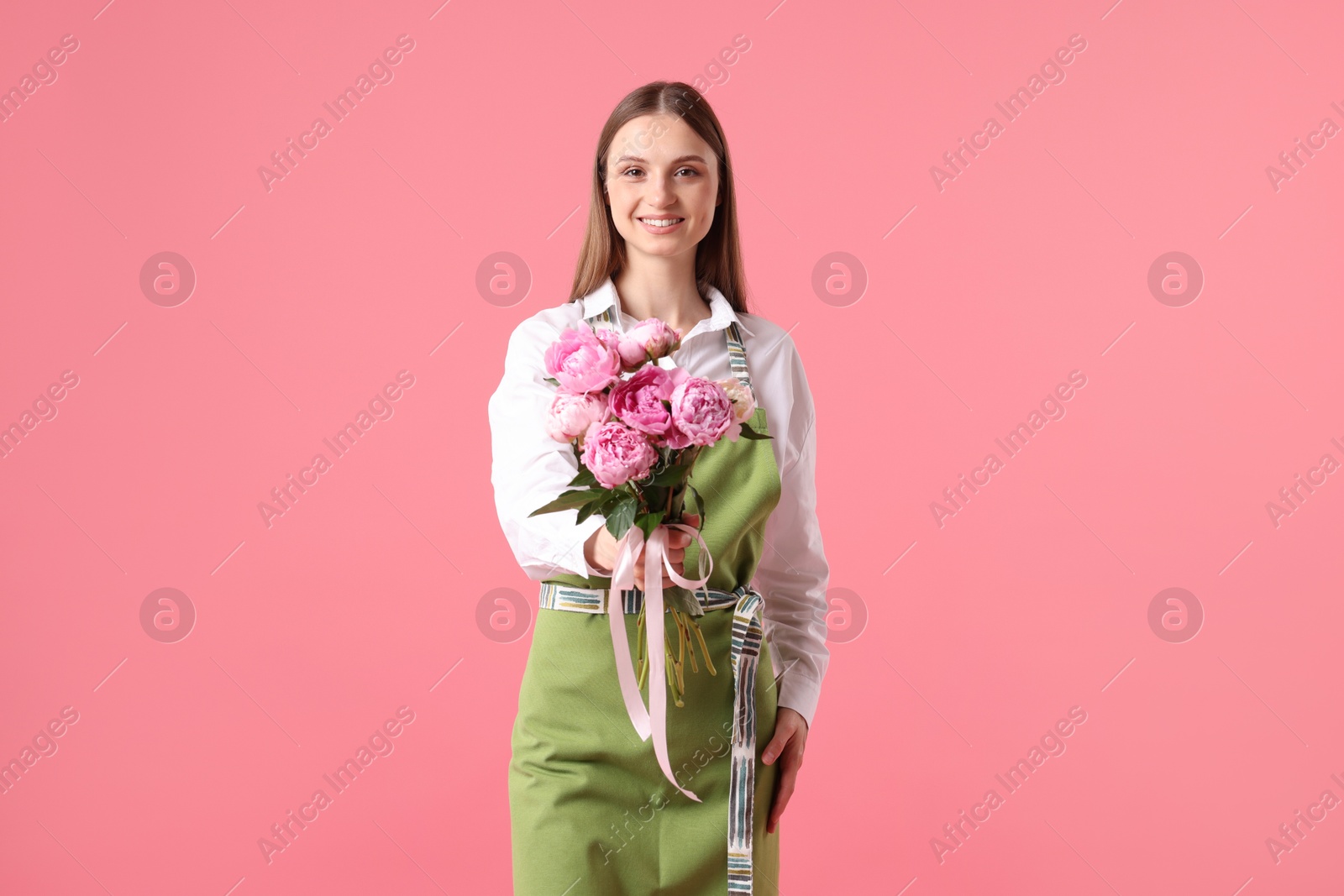 Photo of Florist with beautiful bouquet of peonies on pink background