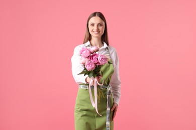 Photo of Florist with beautiful bouquet of peonies on pink background