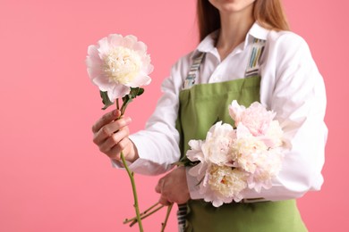 Photo of Florist with beautiful peonies on pink background, closeup. Space for text