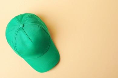 Photo of Green baseball hat on beige background, top view. Space for text