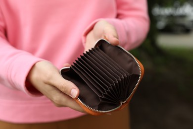 Photo of Woman with open empty wallet outdoors, closeup