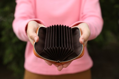Photo of Woman with open empty wallet outdoors, closeup